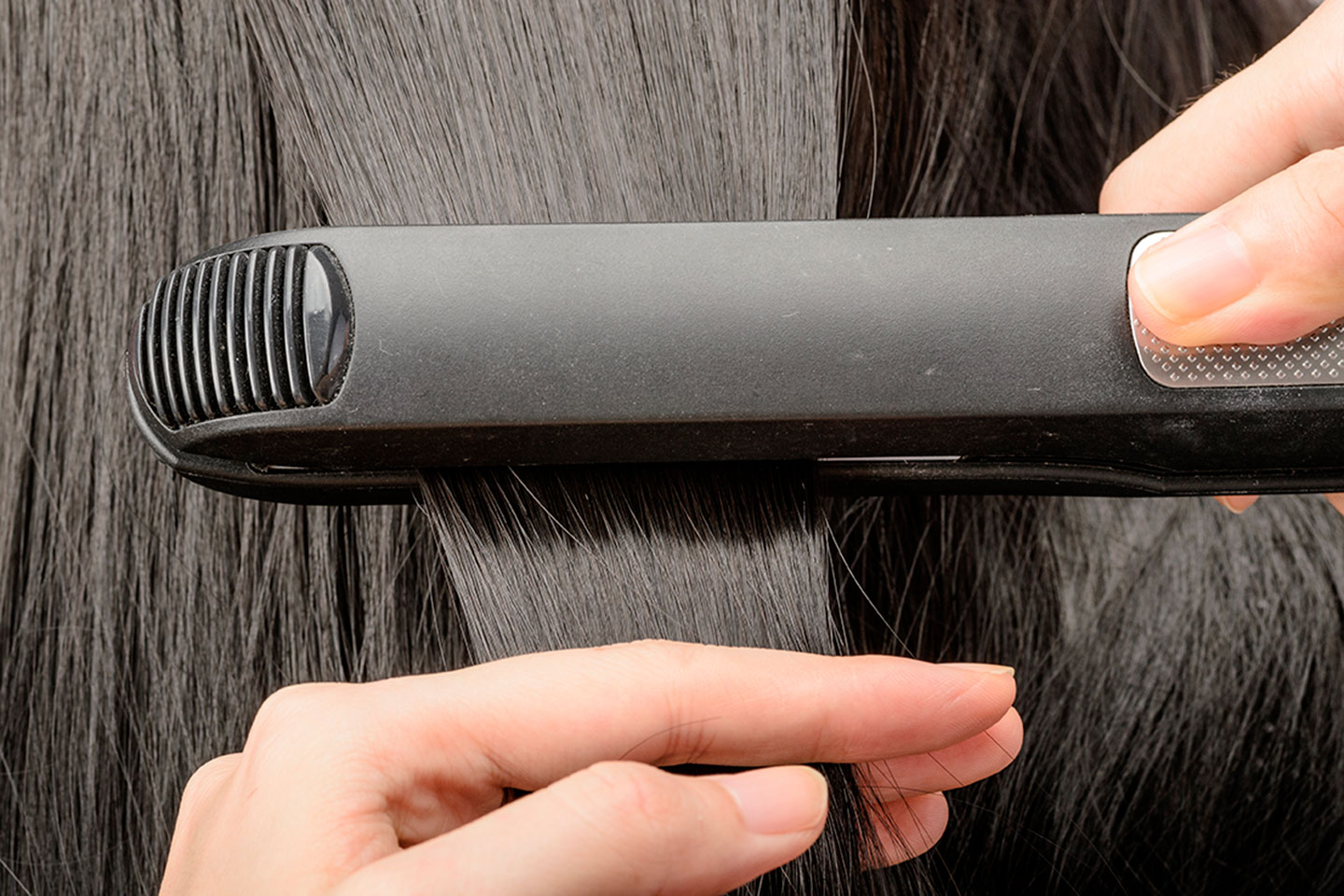 Close-up of a Great Clips stylist straightening a customer's hair with a flat iron