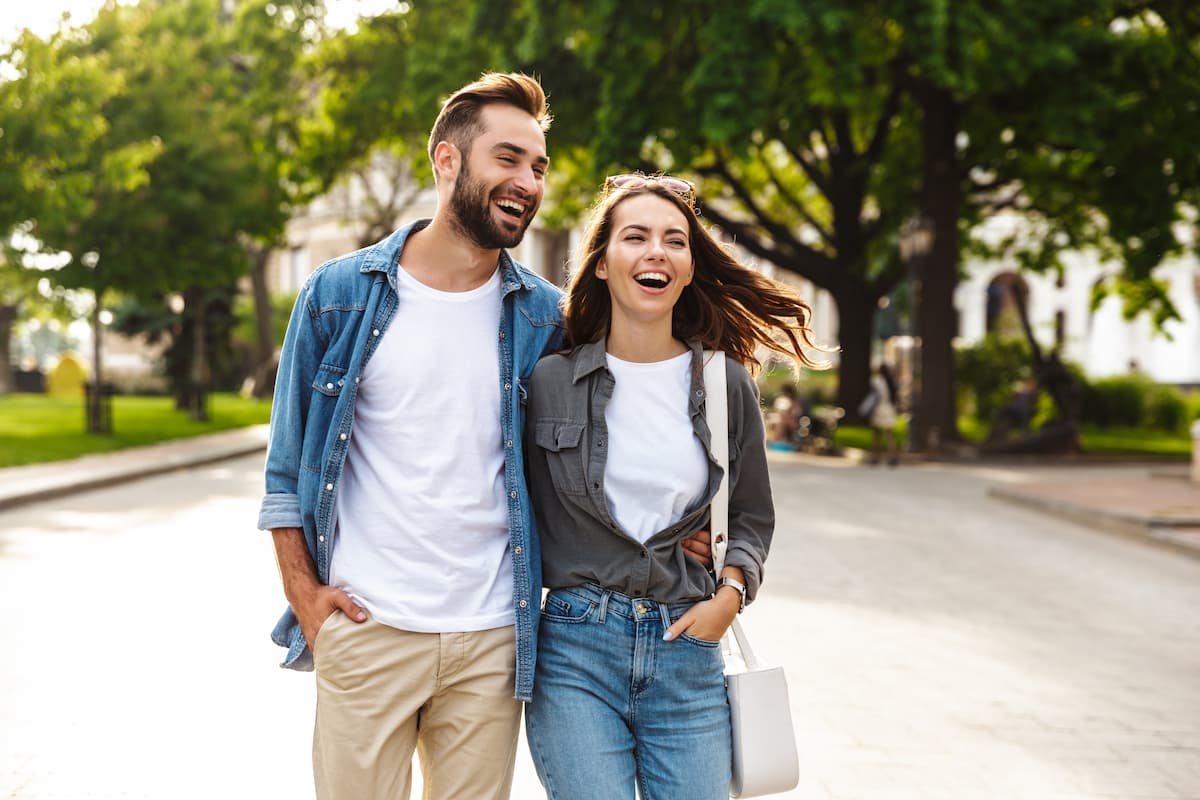 Man and woman laughing and walking together with their arms around each other