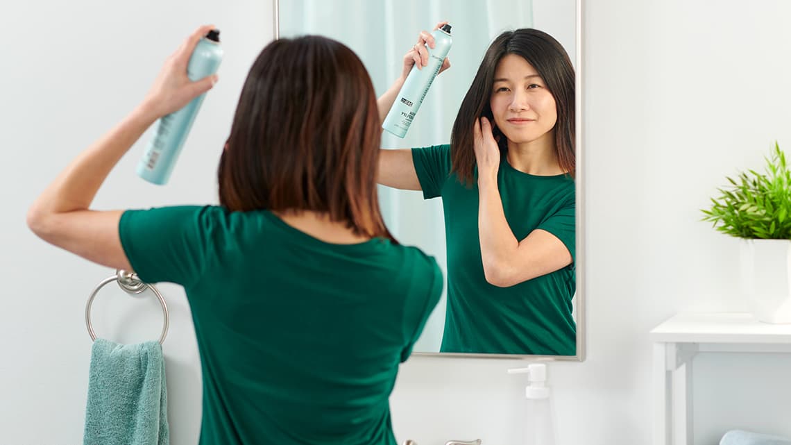 Woman in front of a the mirror using a volumizing hair spray