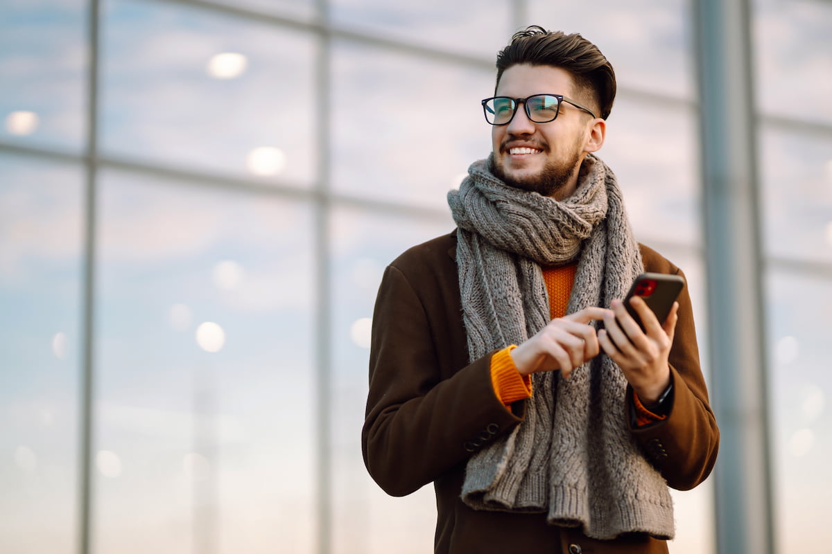 A man wearing a scarf while on his phone A man wearing a scarf while on his phone