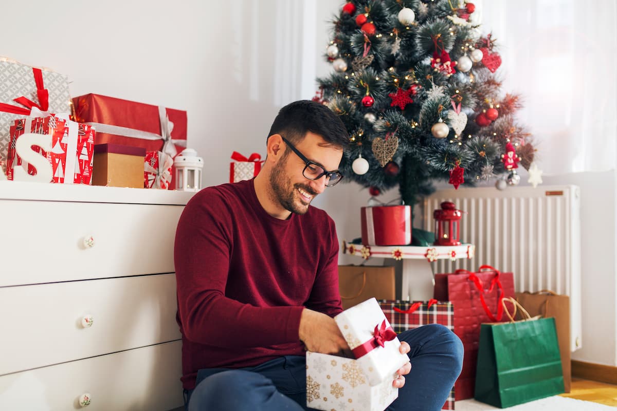 Man sitting on the floor opening up Christmas presents Man sitting on the floor opening up Christmas presents