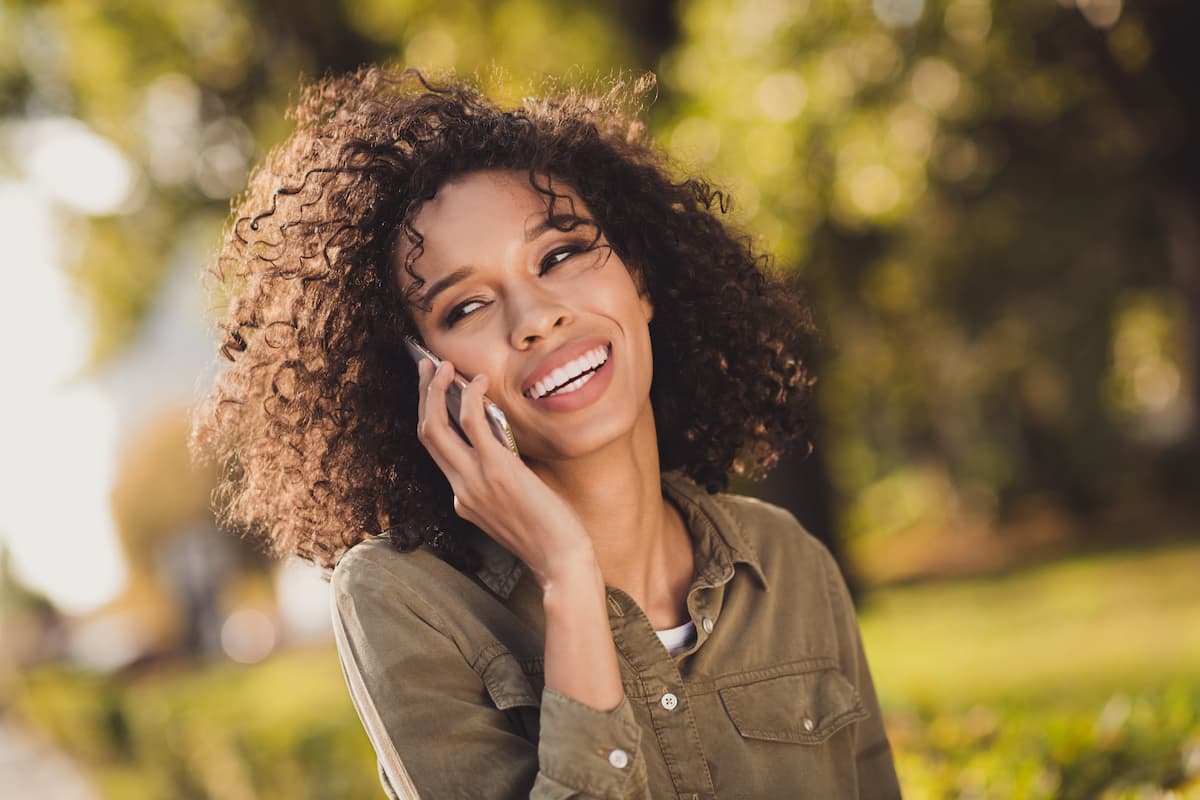 Woman with naturally curly hair smiling and talking on her cell phone
