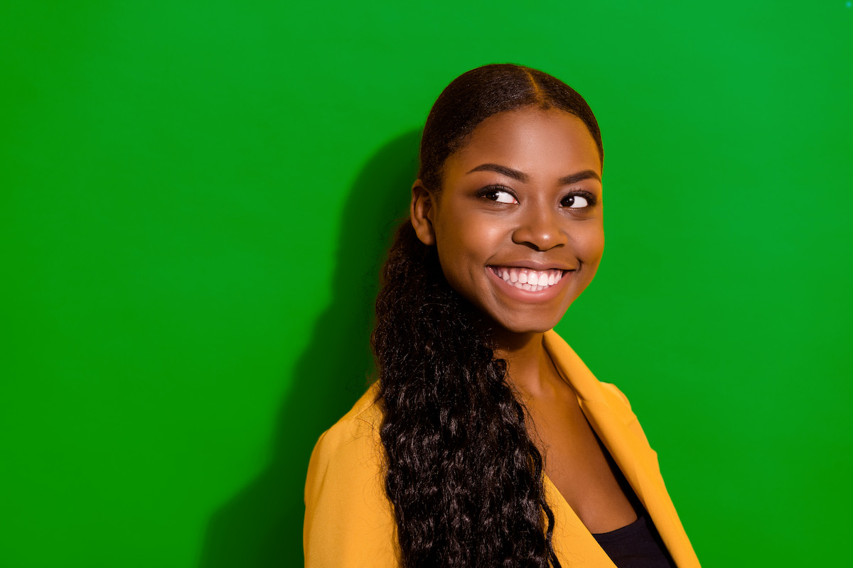 A woman in a yellow jacket looking off camera and smiling A woman in a yellow jacket looking off camera and smiling