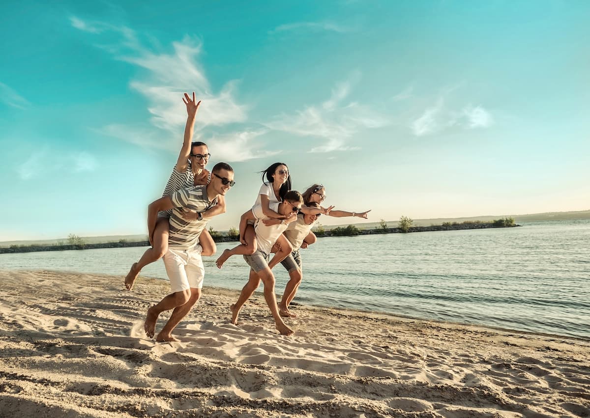 Three young couples piggyback racing on a beach