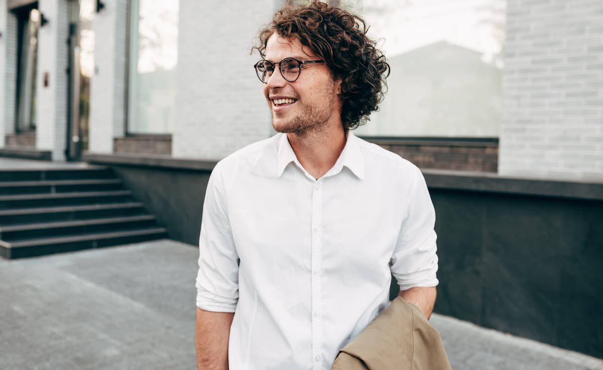 Man with curly hair and glasses smiling