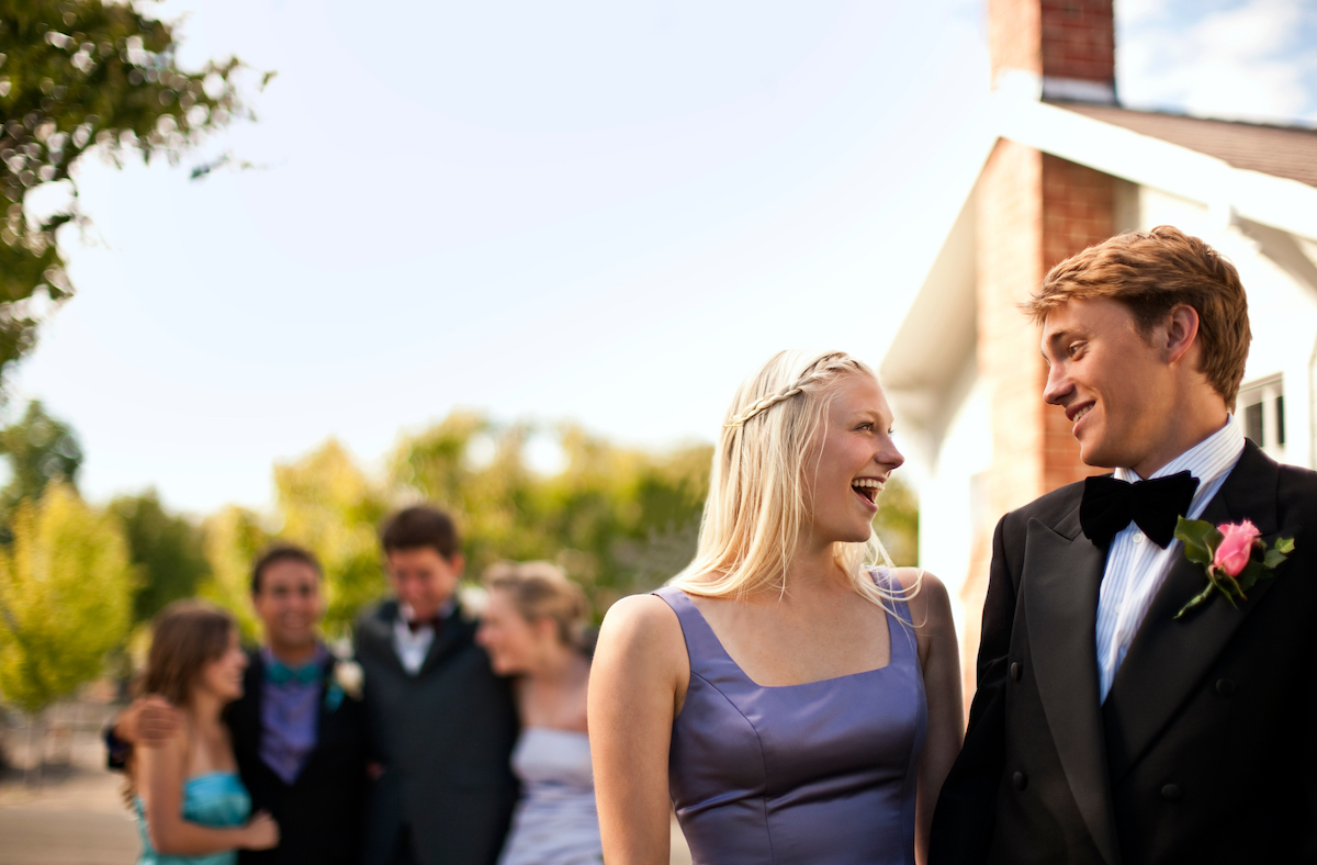Group of high school students in formal wear hugging and laughing