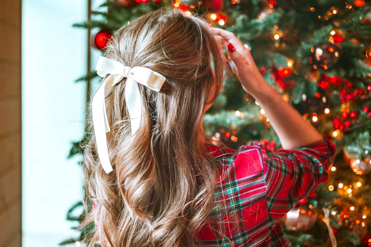 A woman with a hair bow facing a Christmas tree A woman with a hair bow facing a Christmas tree
