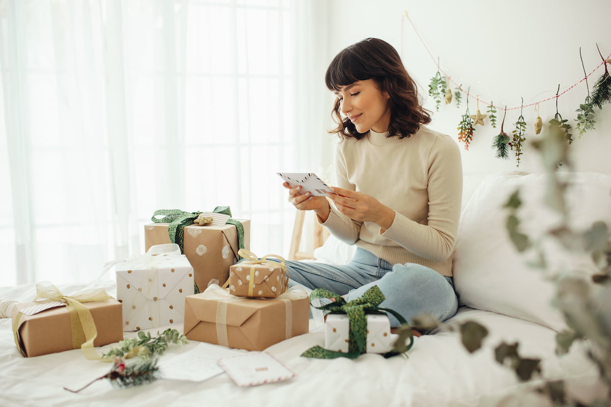 A woman sitting and opening presents on her bed A woman sitting and opening presents on her bed