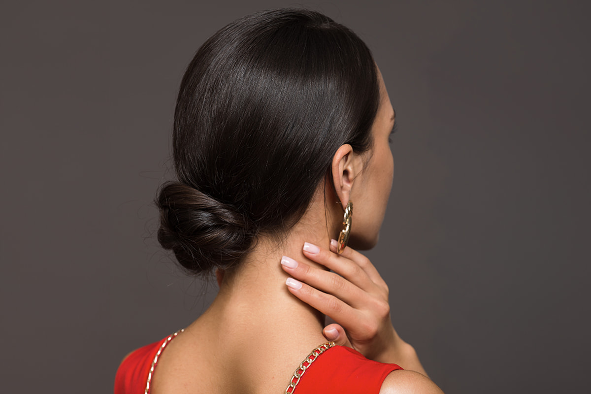 A woman wearing a red outfit facing away with slicked bun A woman wearing a red outfit facing away with slicked bun